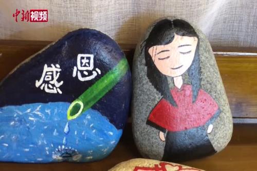 农村妇女用鹅卵石作画