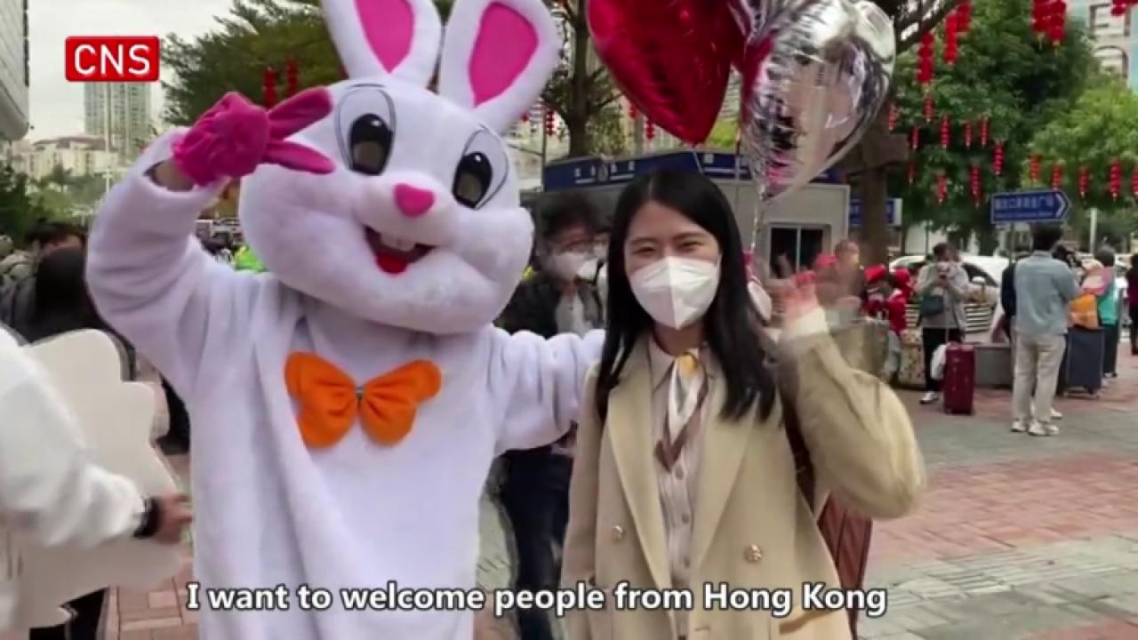Volunteers in rabbit costumes welcome travelers from Hong Kong