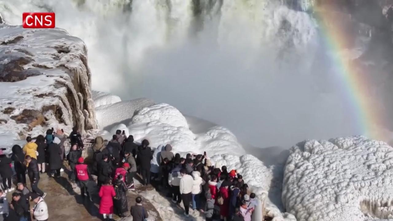 Tourists marvel at the winter splendor of Hukou Waterfall in NW China